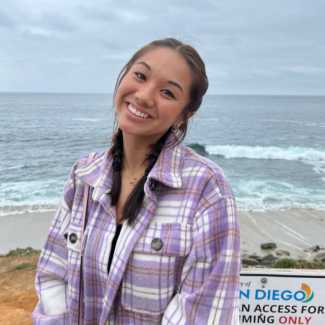 Photo of our Intern smiling in front of beach