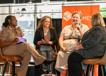 Moderator and three panelists are visible at the WA Women's Foundation Convening are visible. Most are laughing including the speaker and another is clapping.